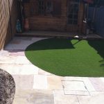 Small garden with patio area and artificial turf leading to garden room