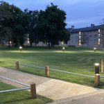 Landscaped area outside student accommodation, which features pathway lighting, mature and young trees, knee-rail fencing and accessibility paving.