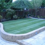 Rear garden with enclosed fencing, planted borders, freshly laid lawn, wall and paved pathway