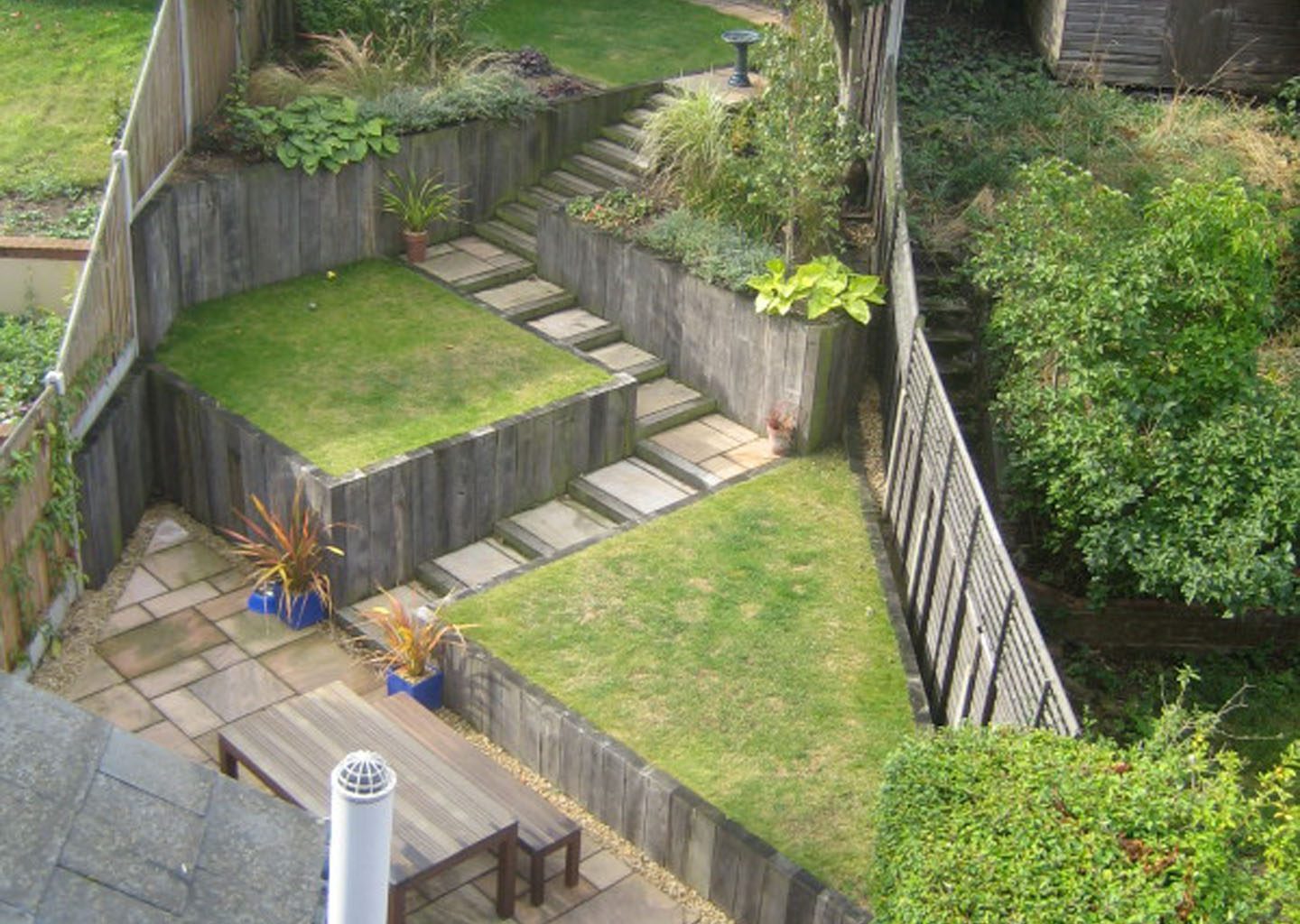 Narrow rear garden with terraced lawn areas, paving and planting