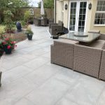 Paved patio area outside patio doors at rear of house with garden furniture and planted containers