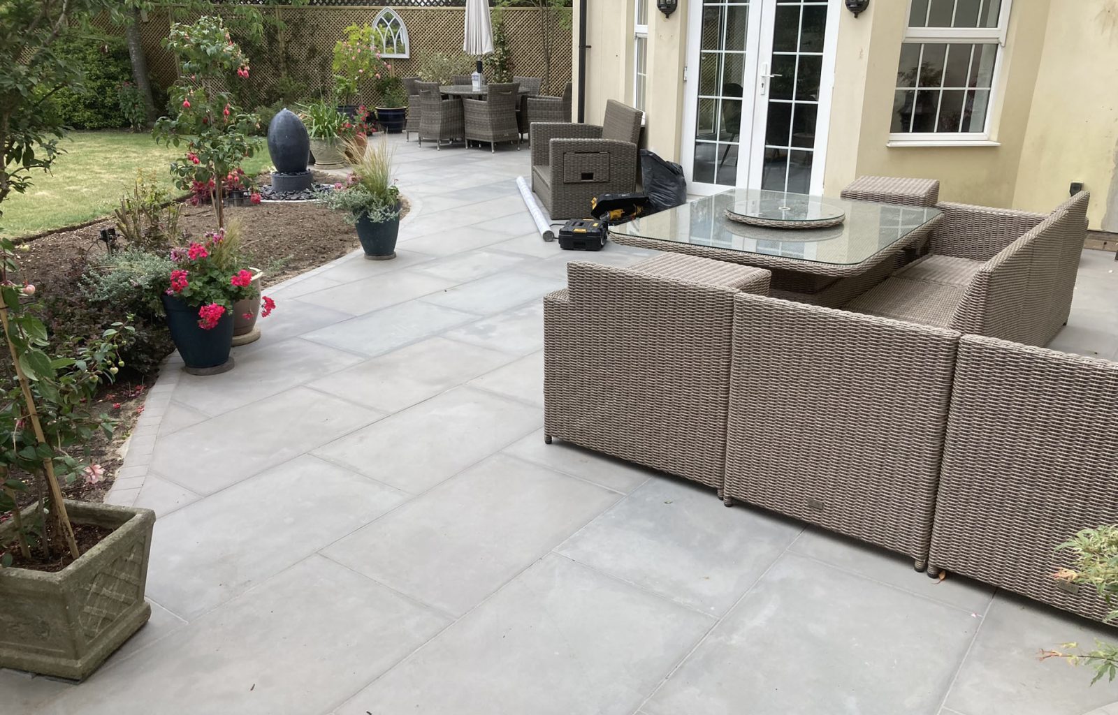 Paved patio area outside patio doors at rear of house with garden furniture and planted containers