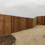 Wooden fencing enclosing shingle driveway