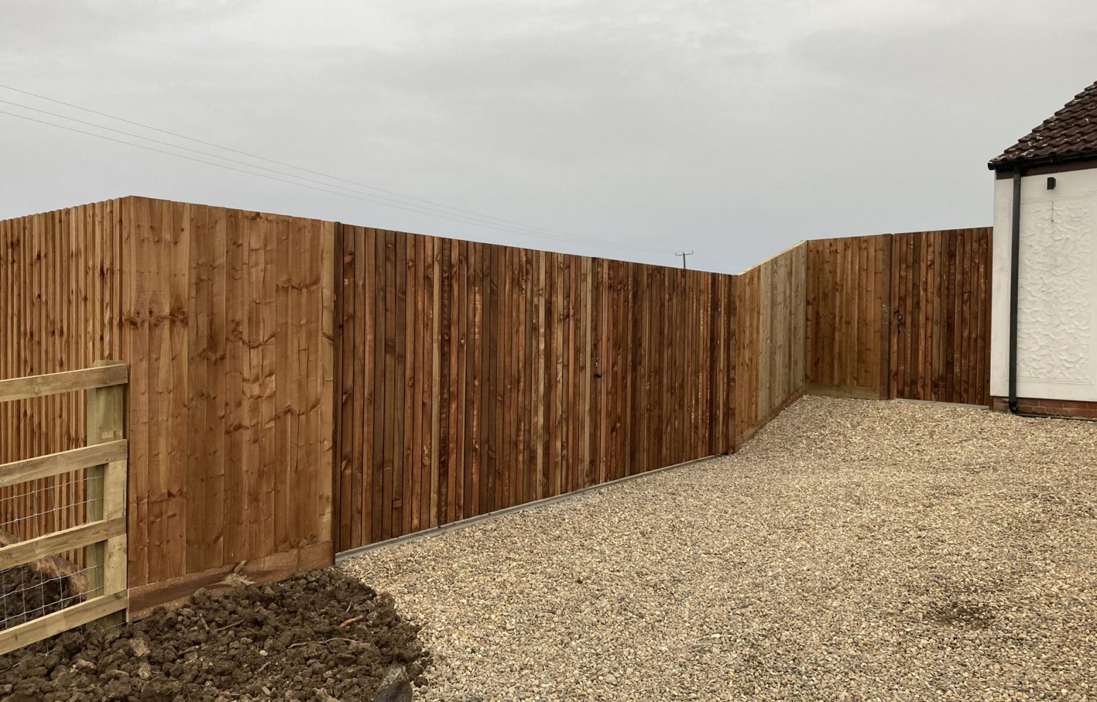 Wooden fencing enclosing shingle driveway