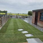 Small garden with freshly laid lawn and paving alongside garage which leads to seating area